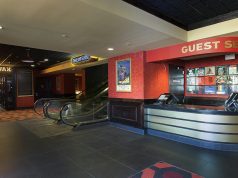 The lobby of Alamo Drafthouse in Downtown Brooklyn. A guest services desk is located to the right, and escalators to the left.