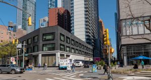 A street corner in Brooklyn showing a building with "The Fresh Grocer - Coming Soon" signage. The storefront appears to be under development at what will become the chain's first NYC location on Fulton Street. The image shows the exterior of the future grocery store in an urban setting.